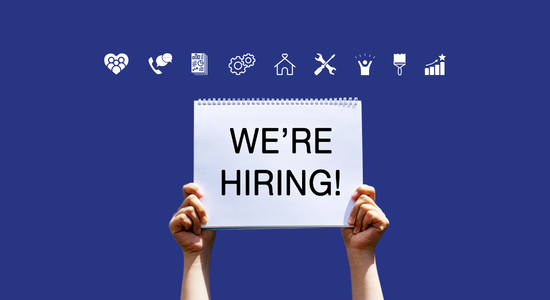 Someone holding up a notepad which says 'We're hiring!"