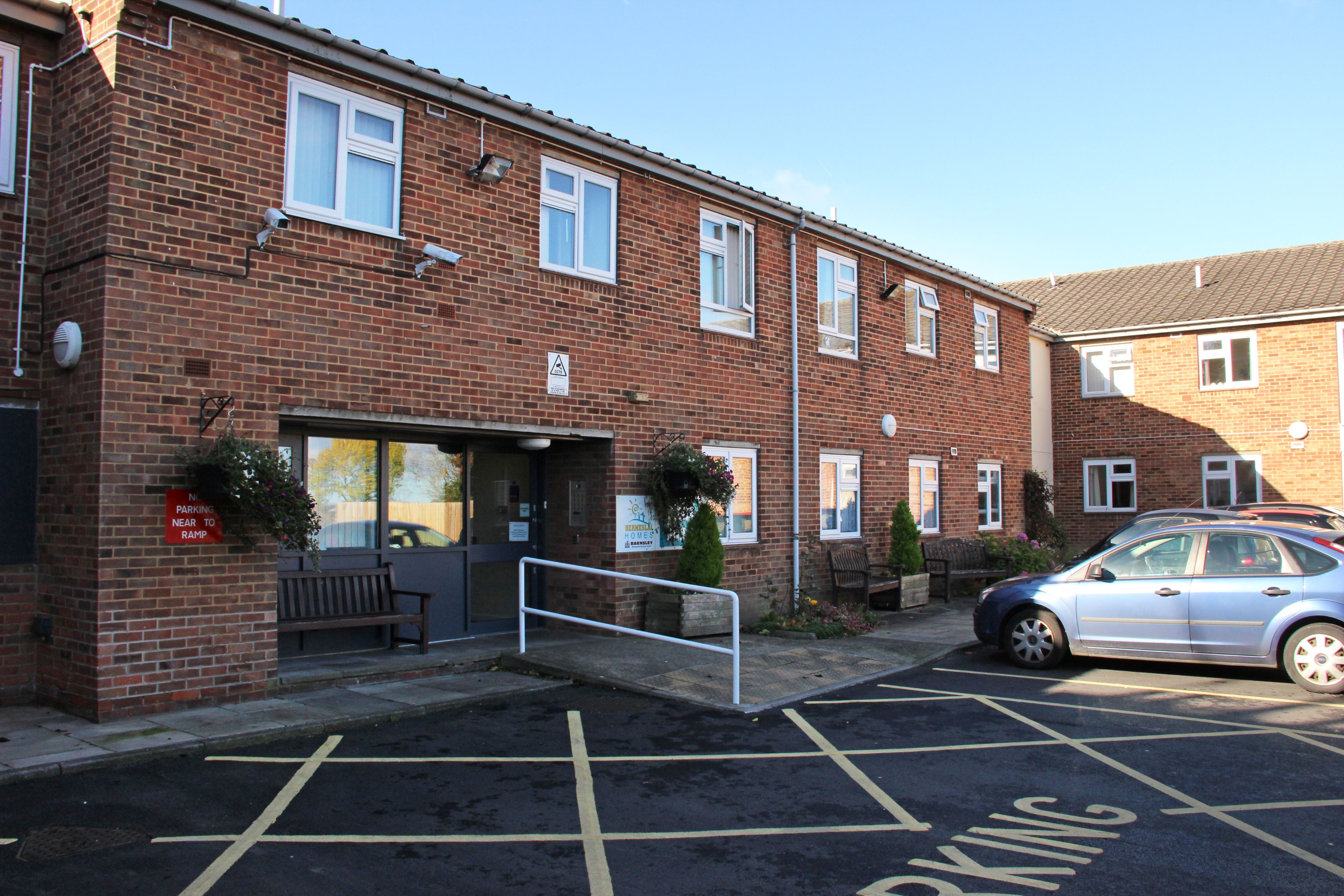 The entrance to Glebe Court with cars parked in different bays.