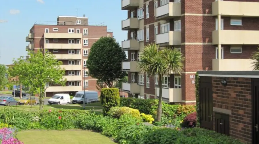 One of Berneslai Homes' properties with vans parked outside next to various trees and plants