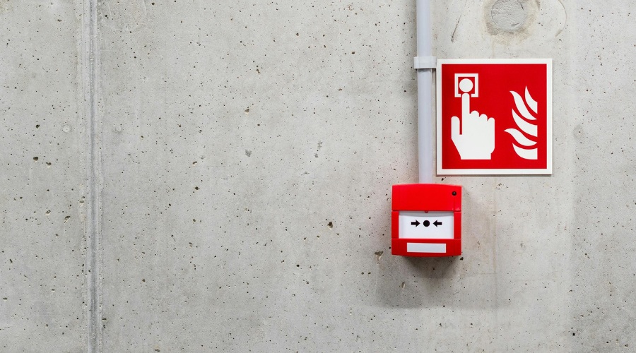 A red fire alarm button on a grey wall
